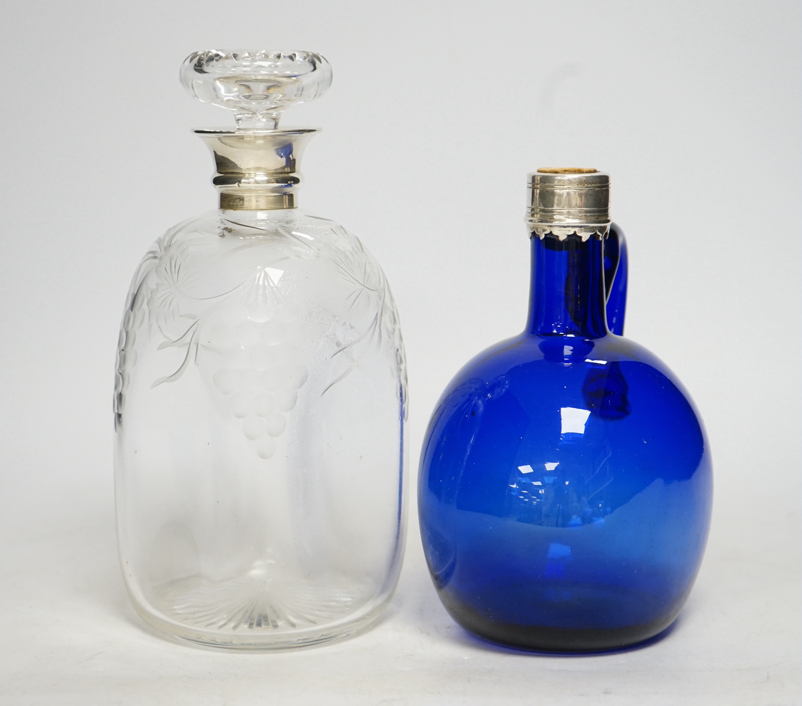 A silver mounted wheel engraved glass decanter and stopper and a white metal mounted Bristol blue decanter (2) tallest 23cm